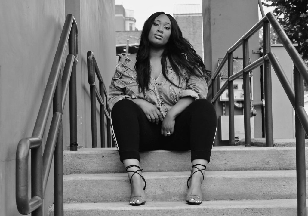 Blogger TheModestGawdesss sits on steps and poses for biography feature by MediaGirlsonTour.com