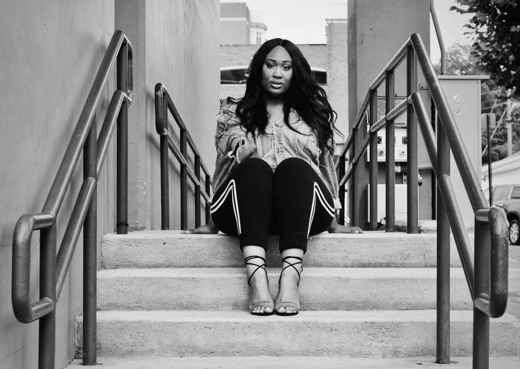 Alexis Prothro sits and poses on the top of stairs at